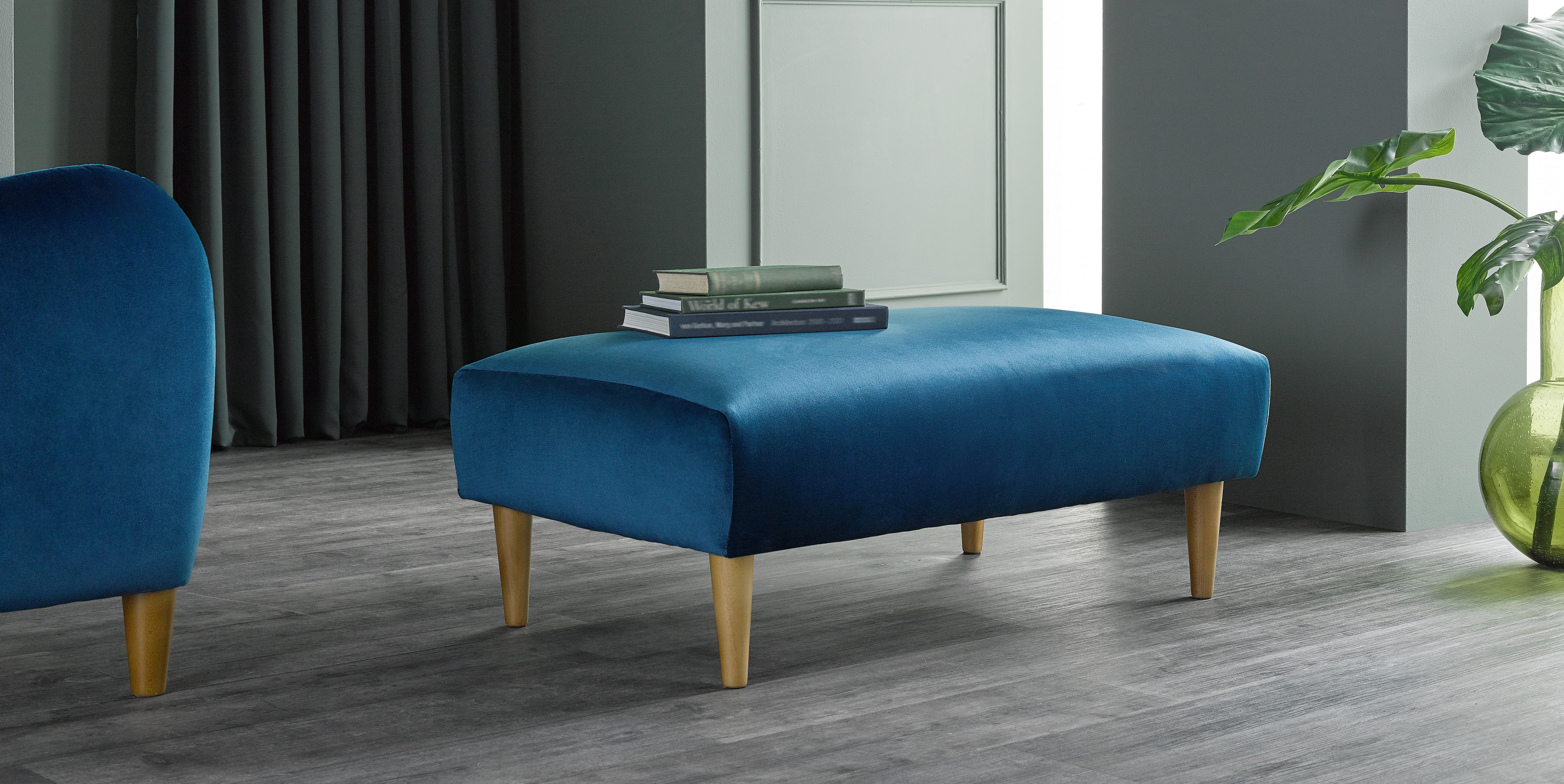 blue velvet footstool in a light grey room